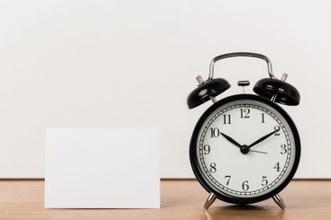 Black vintage alarm clock on wooden table
