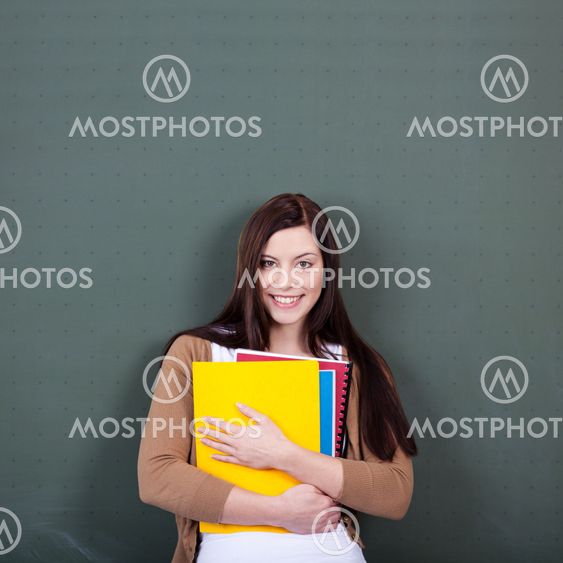 Woman Holding Files Against Chalkboard In Classroom