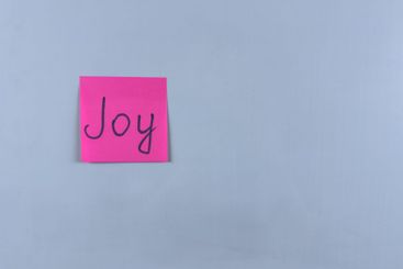 Sticky note with the word Joy written on it, pinned on...