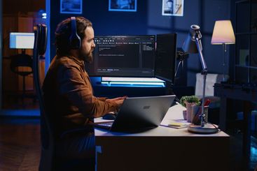 Developer typing complex code in neon lit home office,...