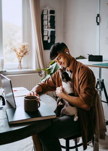 Smiling male freelancer sitting with pet dog at home office