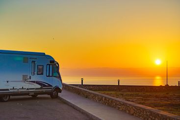 Camper car on coast at sunrise