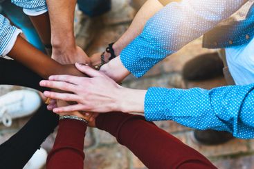 College students, above or hands together in huddle in...