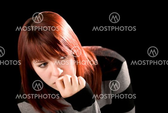 Pensive redhead girl biting nail