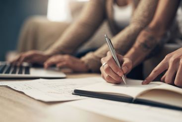 Finance, couple and hands writing in notebook for...