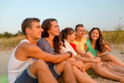smiling friends in sunglasses on summer beach