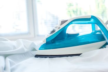 Iron on ironing board on light home interior background