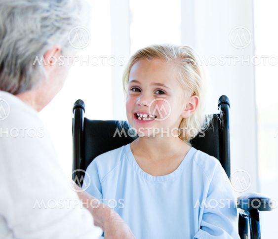 Blond little girl sitting on a wheelchair talking with her grandmother