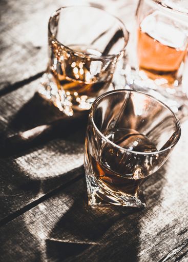 Two whiskey glasses close up on old wooden table
