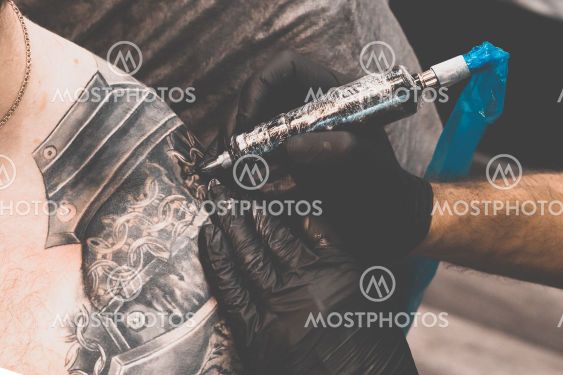 Tattoo salon. The tattoo master is tattooing a man on...