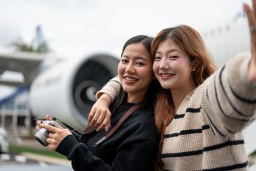 Two female friends, excited for their trip together, are...