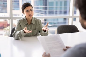 Serious beautiful young businesswoman talking to male...