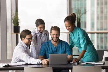Smiling clinic staff members using laptop at workplace