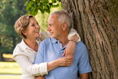 Happy pensioner couple cuddling outdoors