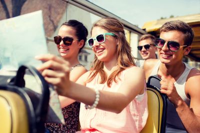 group of smiling friends traveling by tour bus