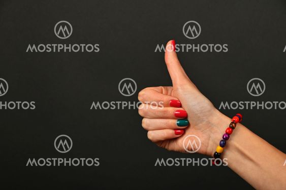 Woman hand shows thumb up gesture over black