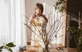 A teenage girl decorates the branches of the house with...