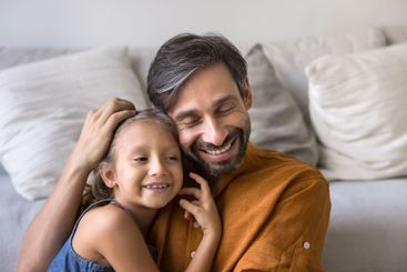 Closeup of loving father cuddling tightly his little 6s...