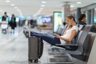 Young female passenger at the airport, using her tablet...