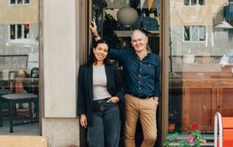 Senior male owner standing with female colleague at store entrance