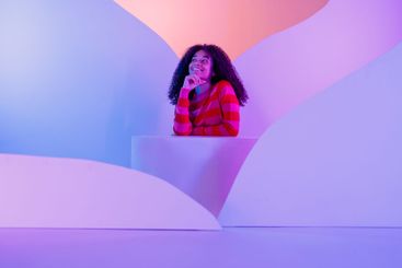 African in sweater sits at white round platform....