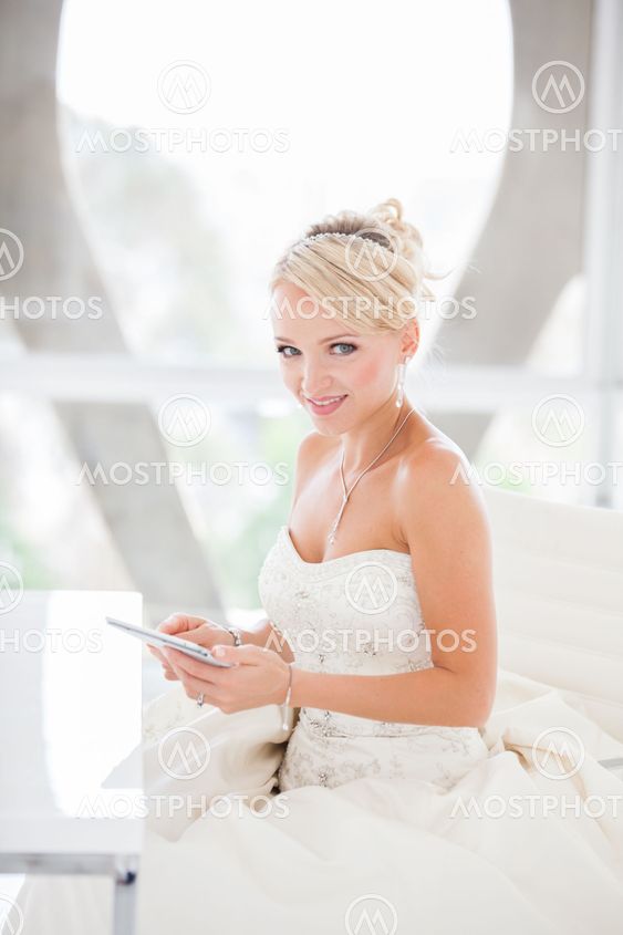 Smiling beautiful blond bride sitting at a table with a Mini touch pad