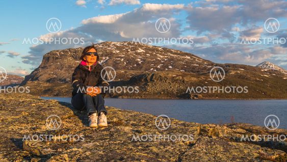 Woman sitting on rock in sunset