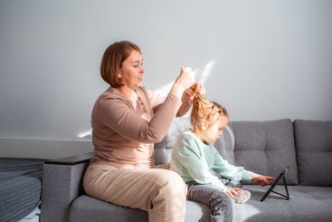 Mother and daughter are sitting on the couch together. A...
