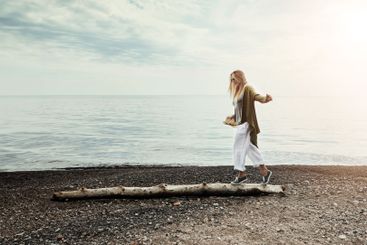 Tree trunk, seaside and woman walking with balance,...