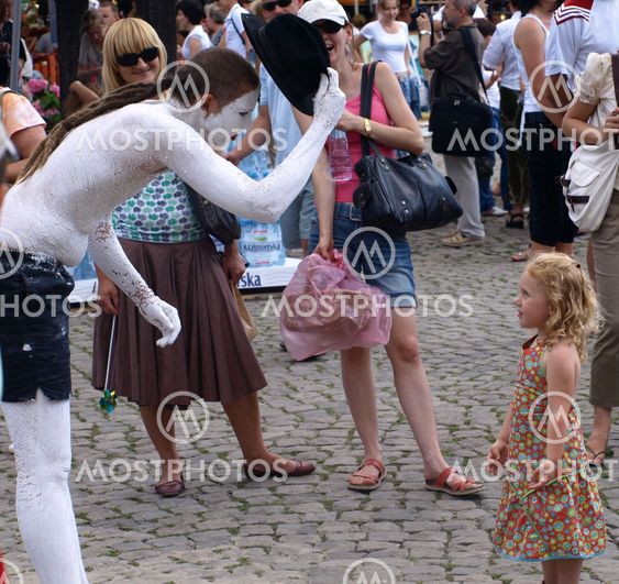 Street actor and young girl (tourist) on Old Market Place in Kazimierz Dolny, Poland