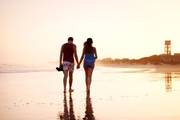 Couple, holding hands and walking together at beach for...