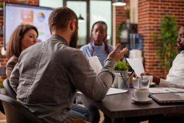 Caucasian man speaking to his colleagues