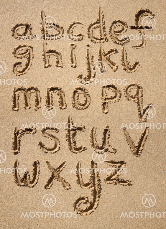 The alphabet written in sand on a beach.