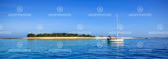 Boat and beautiful Fiji atoll island with white beach