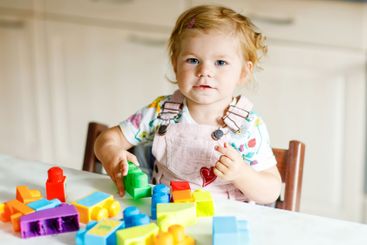 Adorable toddler girl with educational toys in nursery...