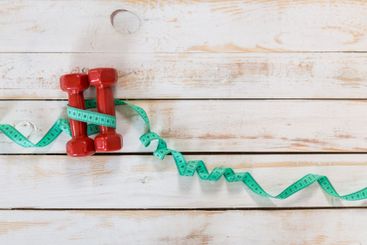 Fitness concept with dumbbells and measuring tape