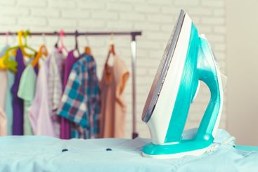 Iron on ironing board on light home interior background