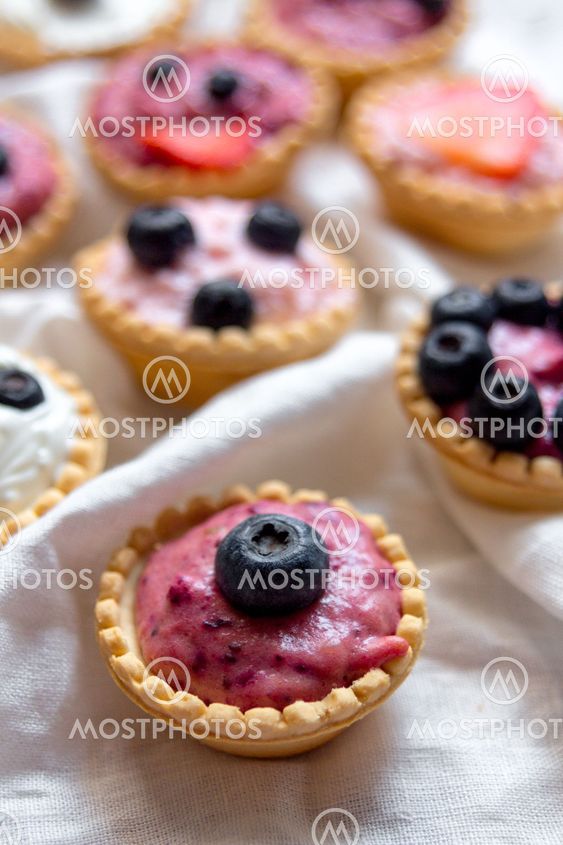 Sweet mini tartlets with cream and berries on white...