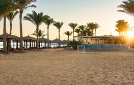 Sunset at a tranquil beach in a coastal resort with palm...