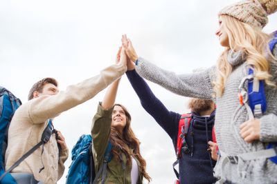 group of smiling friends with backpacks hiking