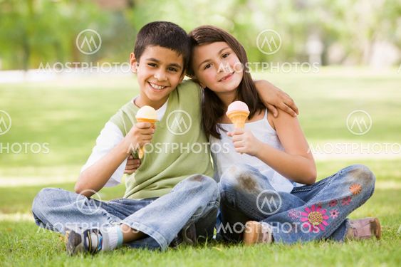 Two children eating ice cream in park