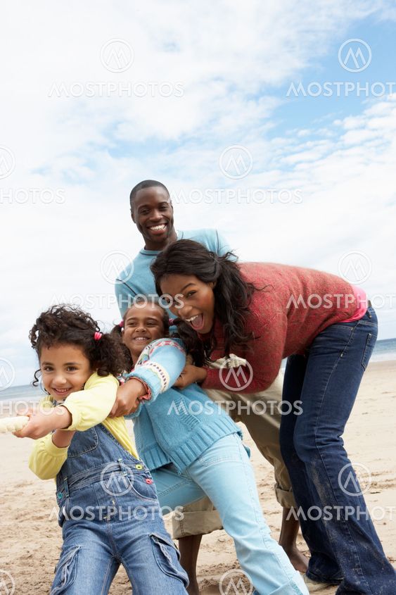 Family playing tug of war on beach