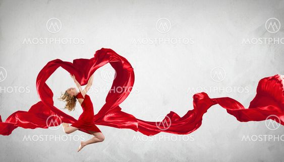 Dancing young woman with flying fabric