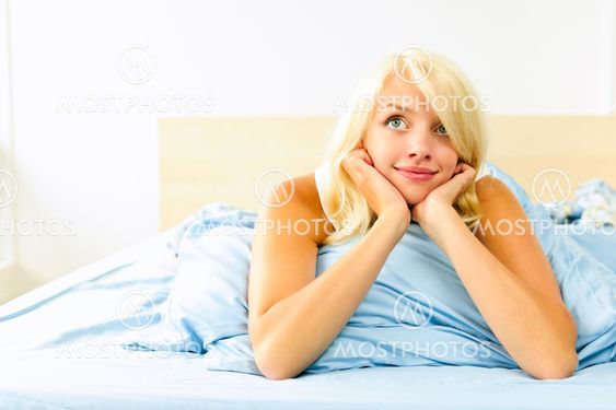 Pretty woman laying in bed daydreaming