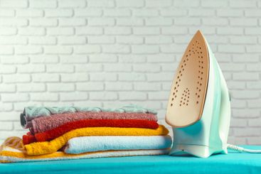 Iron on ironing board on light home interior background