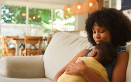 Mother Holding Baby in Cozy Living Room During Daytime