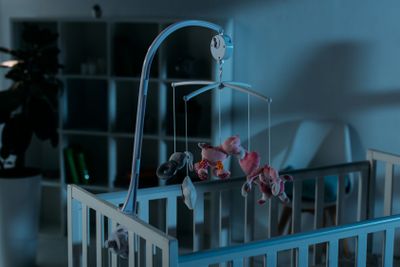 Crib and mobile with toy animals in dark room