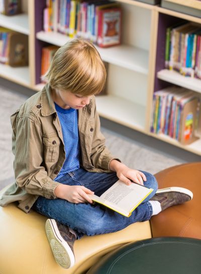 Boy Reading Book In School Library