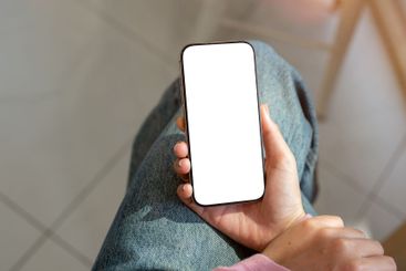 A close-up top view of a woman in jeans sitting indoors...