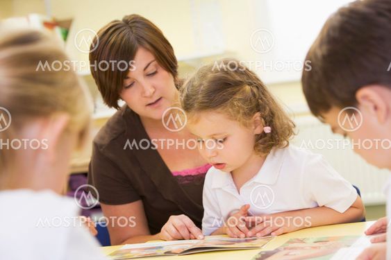 Schoolchildren and their teacher reading in a primary class